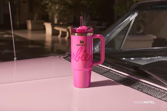 Pink tumbler with handle on a car hood, featuring a logo and text. EA Supplements