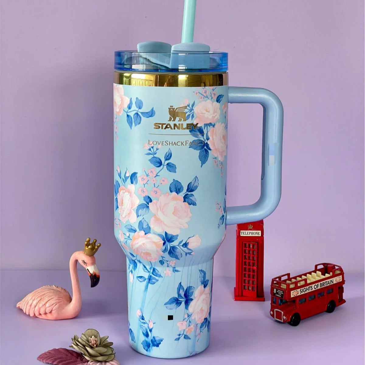 Floral-patterned Stanley tumbler with a handle on a purple background